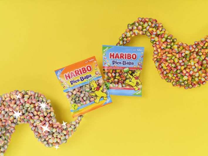 Ein Beutel HARIBO Pico-Balla und ein Beutel HARIBO Pico-Balla Sauer auf gelbem Hintergrund.