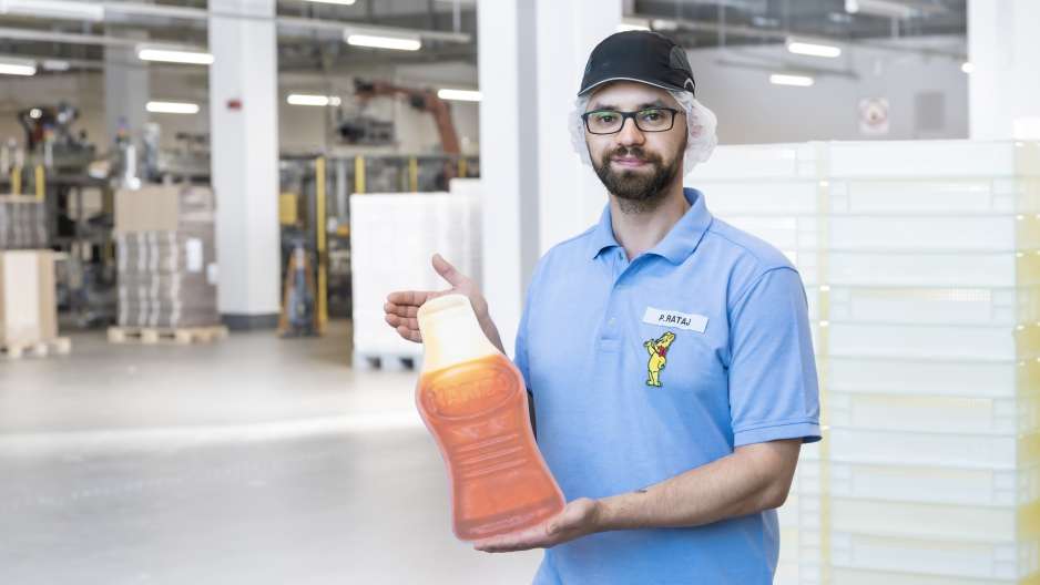 Mitarbeiter in der Produktion hält Cola-Flasche in der Hand