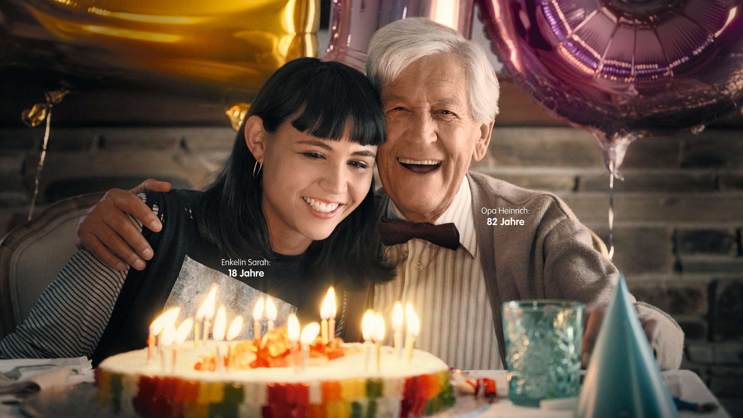 Enkelin und Großvater freuen sich über Kuchen mit Kerzen und Goldbären.