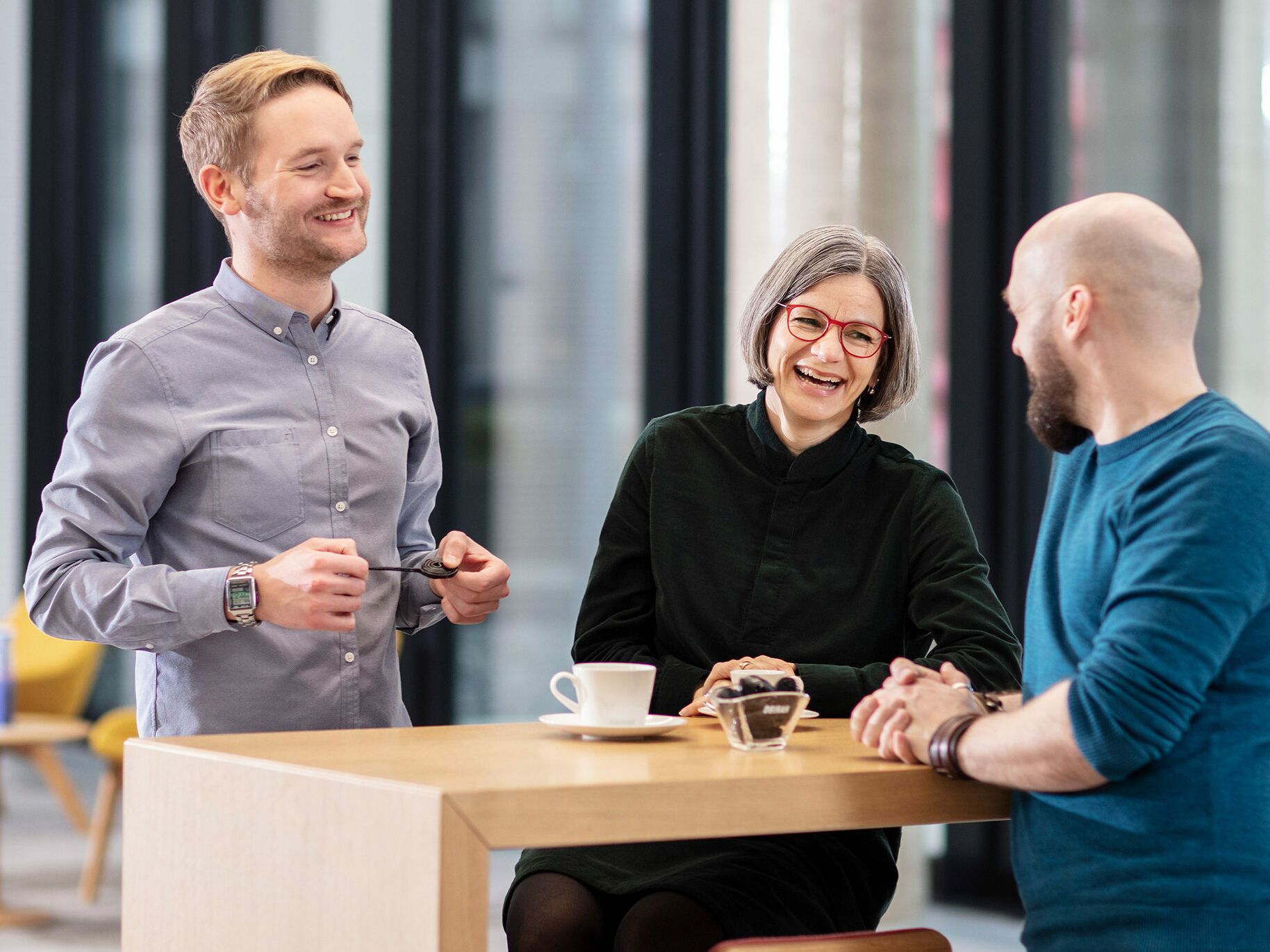 Drei Mitarbeiter unterhalten sich in der Cafeteria