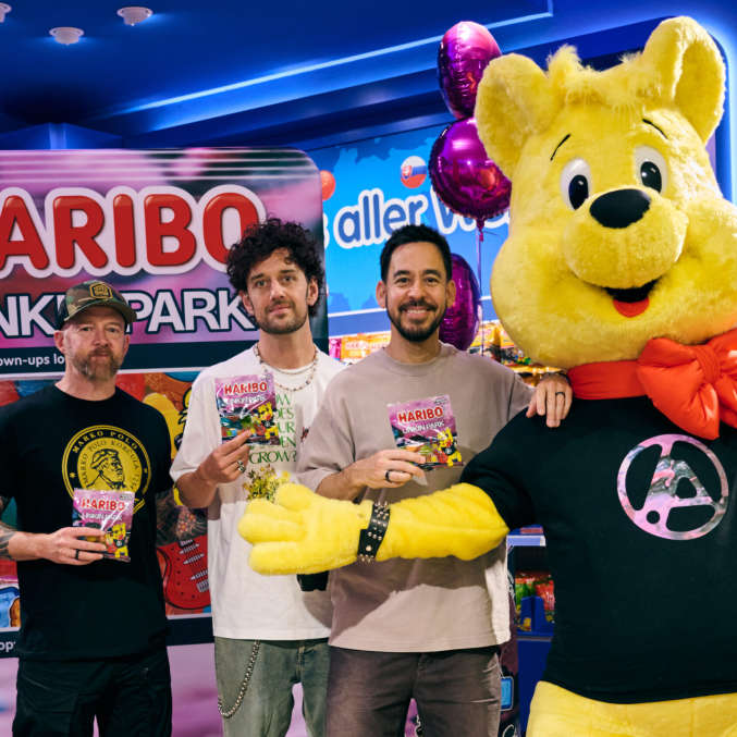 Drei Mitglieder der Band Linkin Park zusammen mit dem gelben HARIBO-Goldbären und ihrer Fruchtgummi-Sonderedition im HARIBO Shop Berlin.