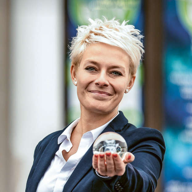 Smiling employee holding small glass ball up to the camera