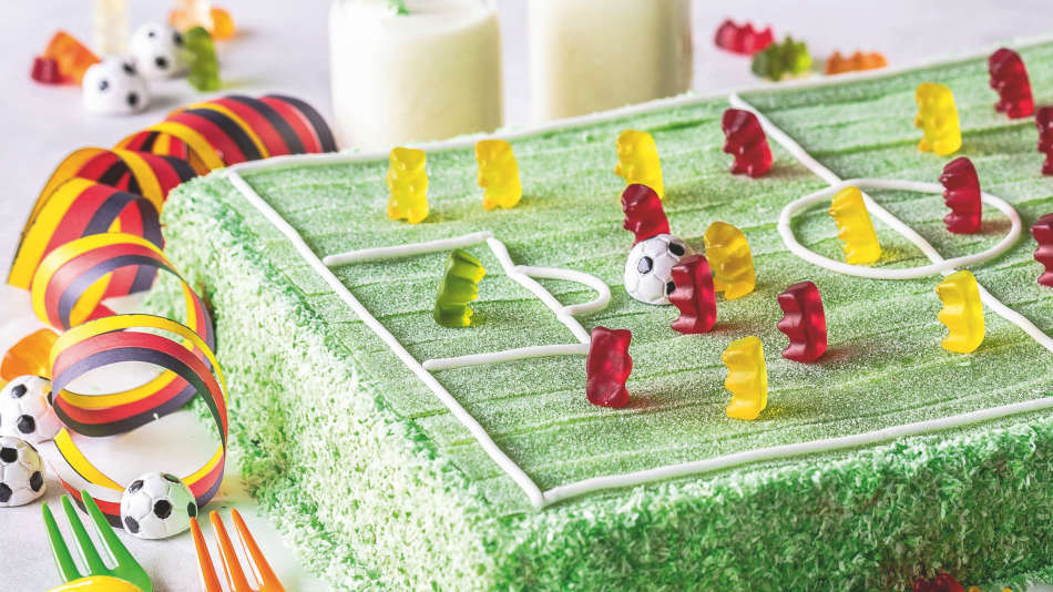 Rechteckiger Kuchen mit grünem Spielfeld aus Pasta Frutta und Goldbären als Spielern