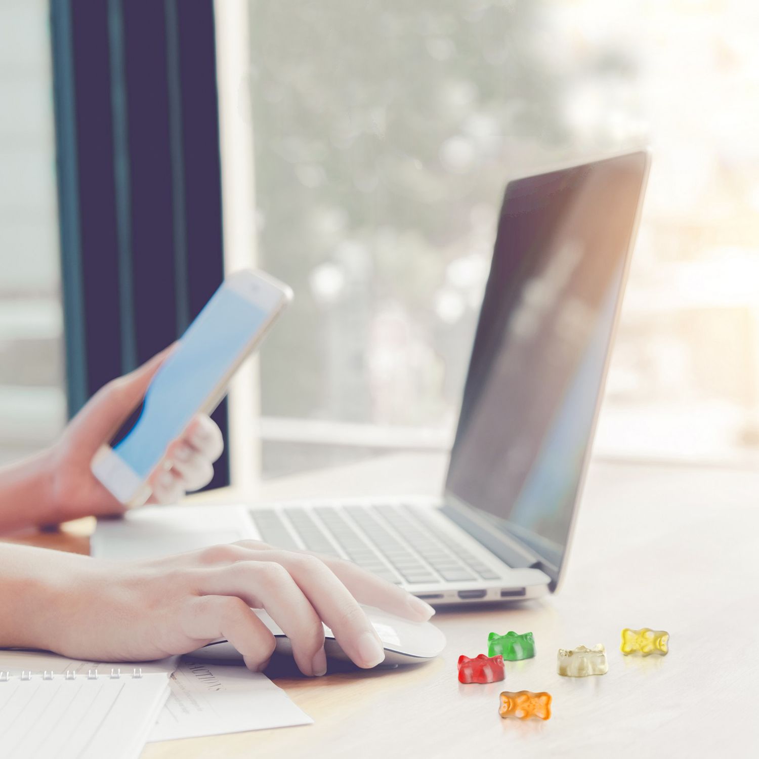 Hands operating a smartphone and laptop