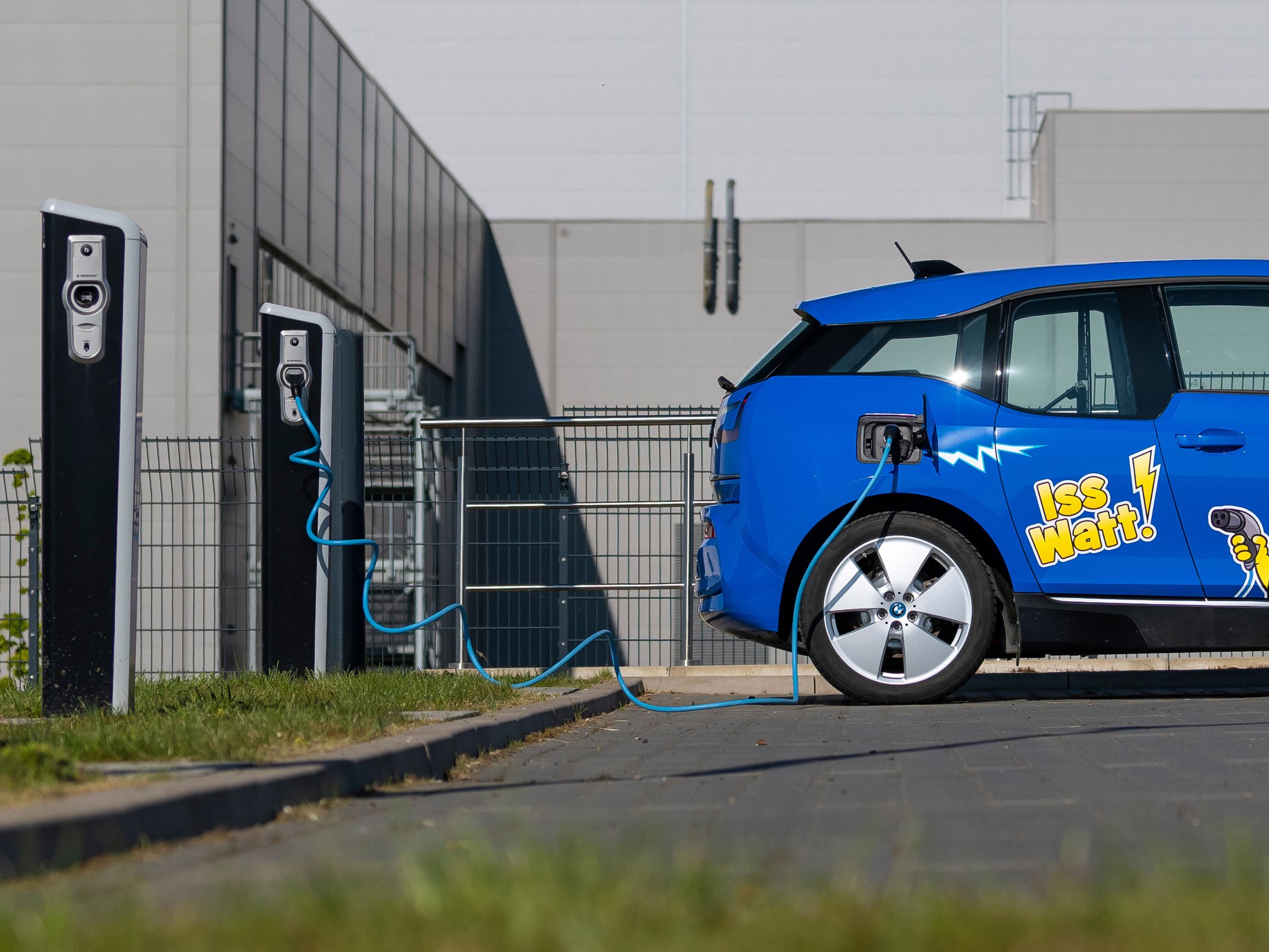 coche eléctrico azul con branding HARIBO delante de un punto de recarga