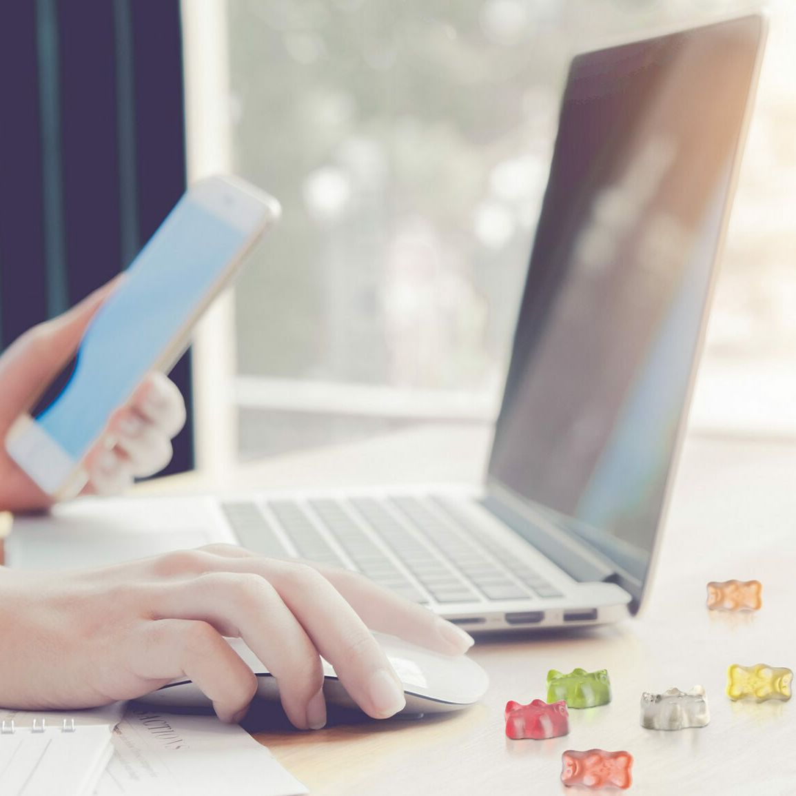 Schreibtisch mit Laptop, Smartphone und Goldbären