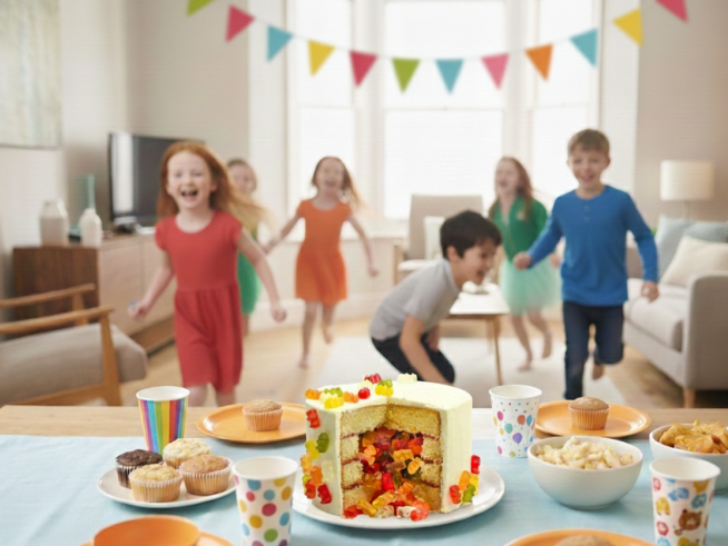 Eine Gruppe von Kindern im Alter von 6 bis 7 Jahren tanzt fröhlich in einem hellen Raum mit einer Geburtstagstafel im Vordergrund. Der Text "6 bis 7 Jahre" steht in großen, gelben Buchstaben daneben und verweist auf Kinderspiel Geburtstag Ideen für diese Altersgruppe. Die liebevoll dekorierte Tafel mit Snacks und Naschereien lädt zum Feiern und Spielen auf der Kinderparty ein.