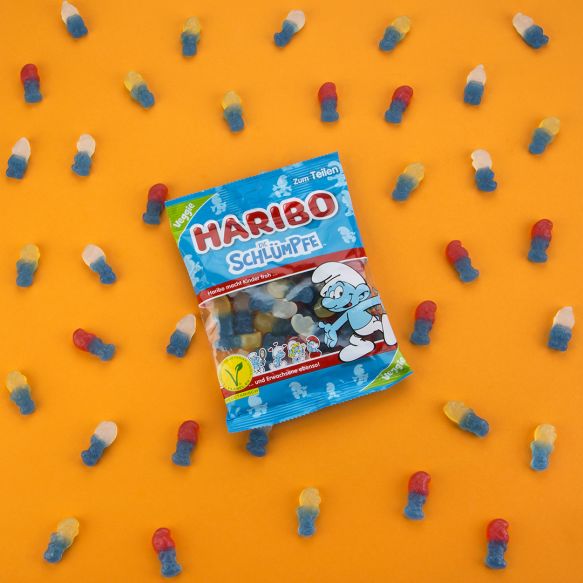 HARIBO Schlümpfe Verpackung und Produktstücke auf orangen Hintergrund