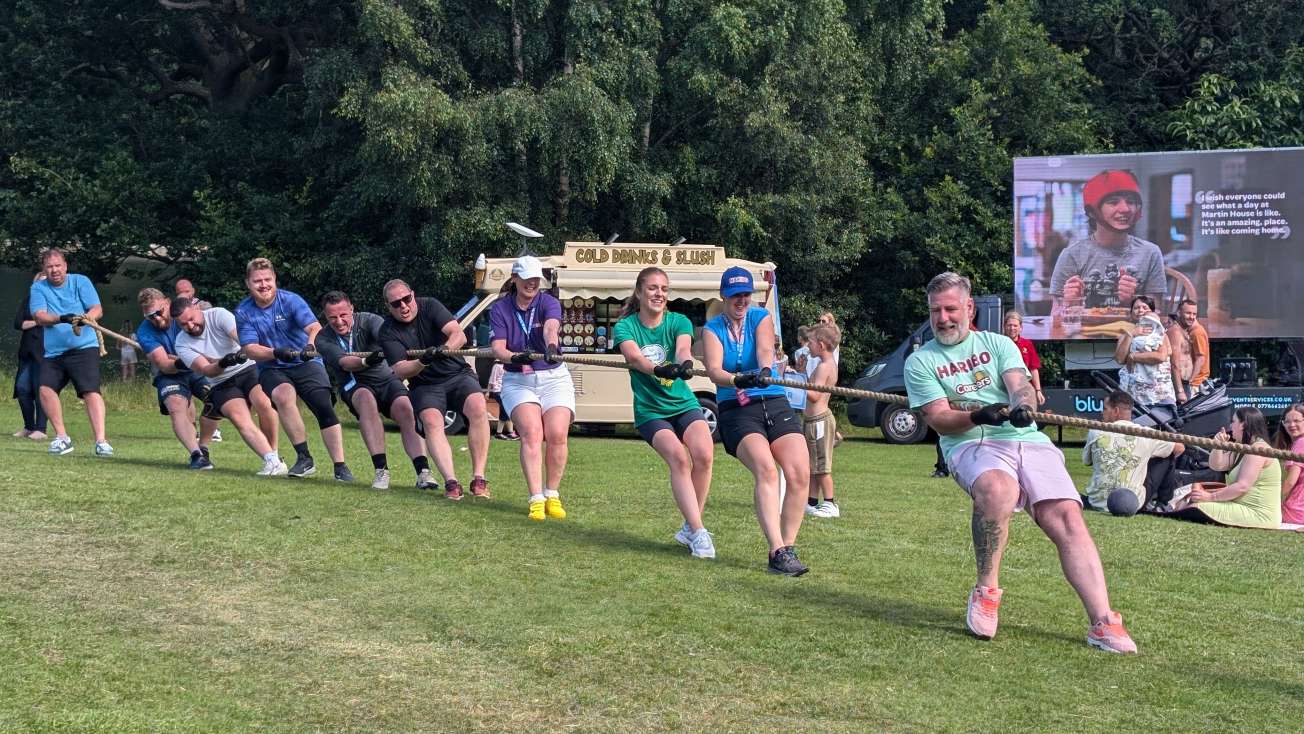 Team of men and women take part in a tug-of-war.