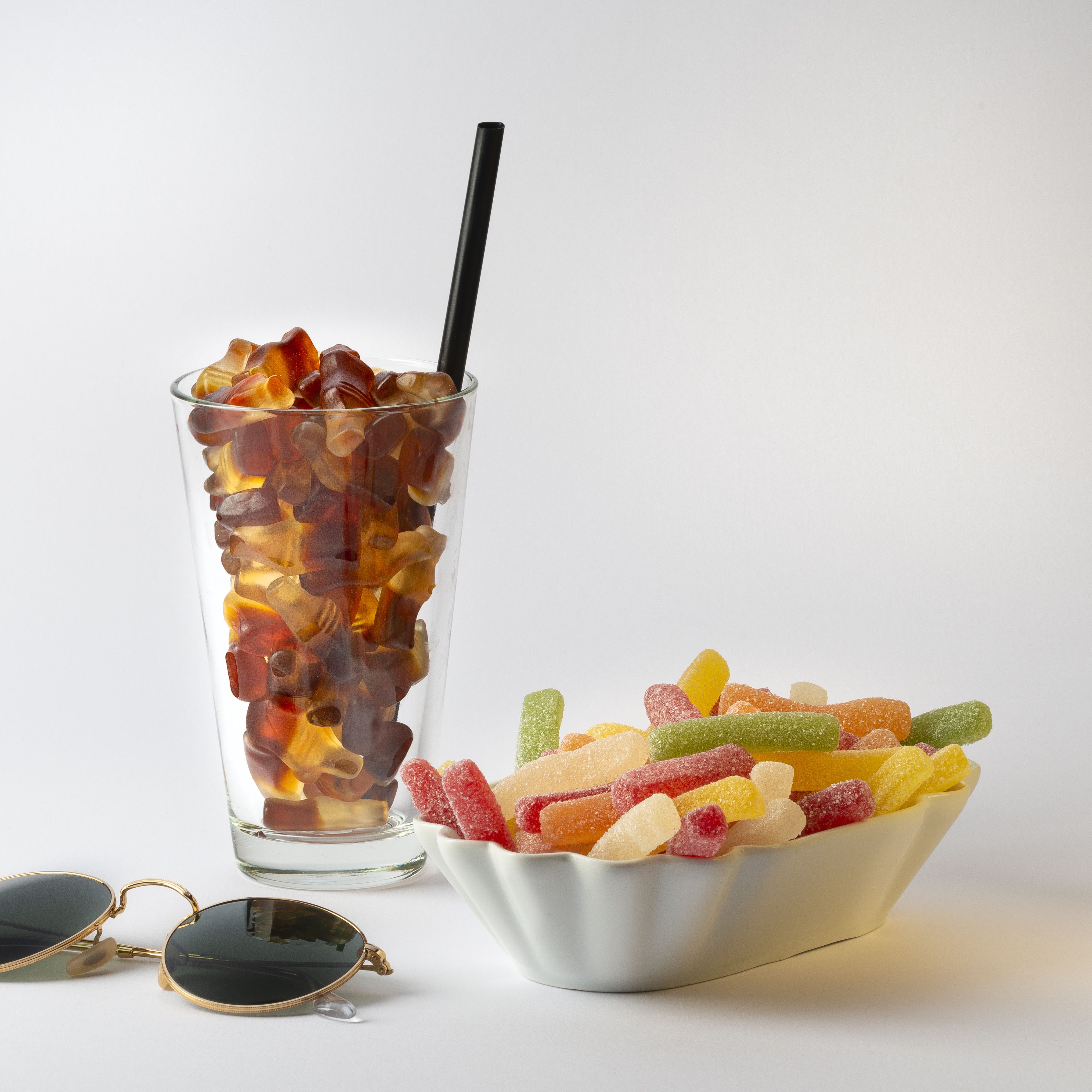 Happy Cola Produktstuecke im Glas und Saure Pommes in einer Schale