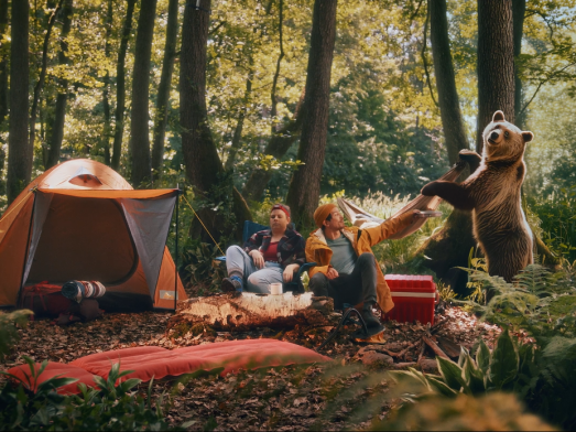 Eine Campingszene in der Natur mit zwei Campern und einem KI-generierten Bären