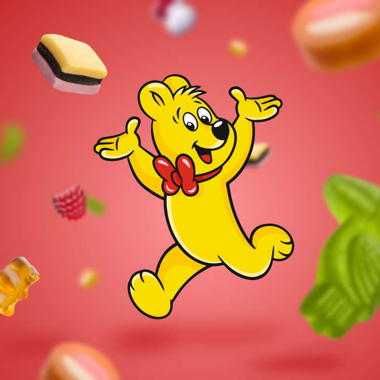 Fliegende HARIBO Produktstücke und laufender HARIBO Goldbär auf rotem Hintergrund