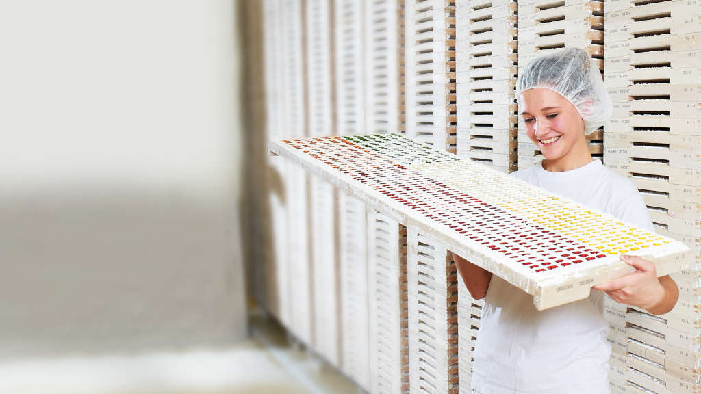 Работница рассматривает готовые фигурки из фруктового мармелада