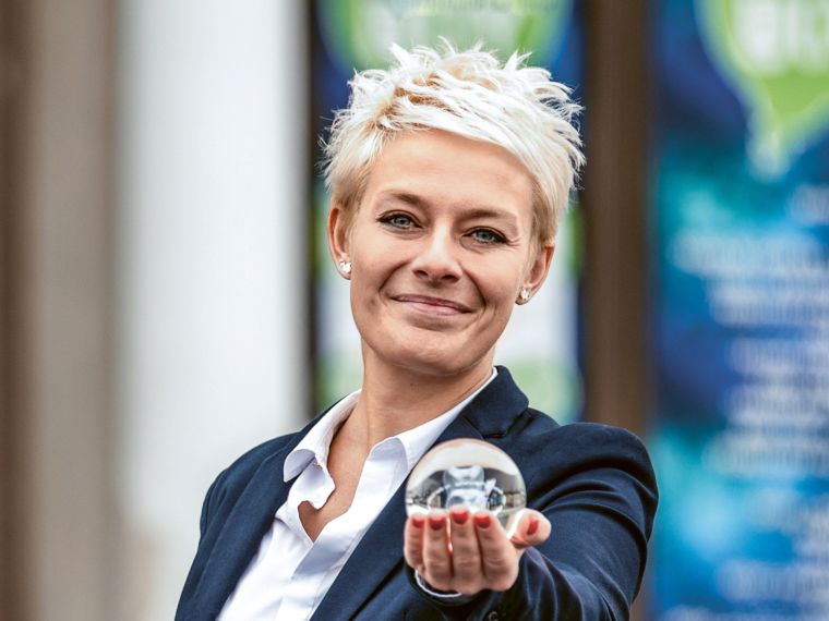 Smiling employee holding small glass ball up to the camera