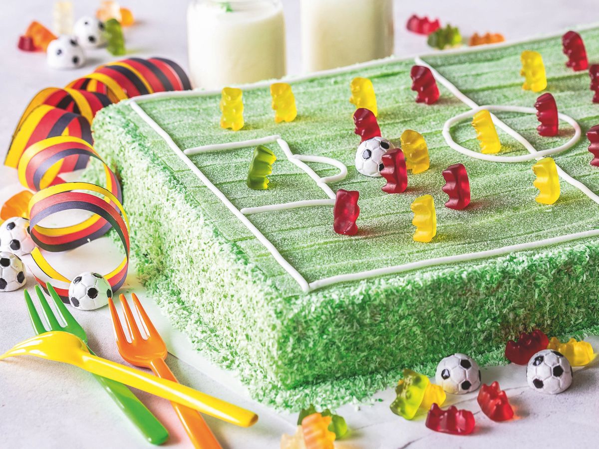 Rechteckiger Kuchen mit grünem Spielfeld aus Pasta Frutta und Goldbären als Spielern