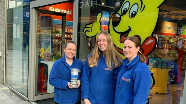 Three women with charity tin in front of HARIBO store