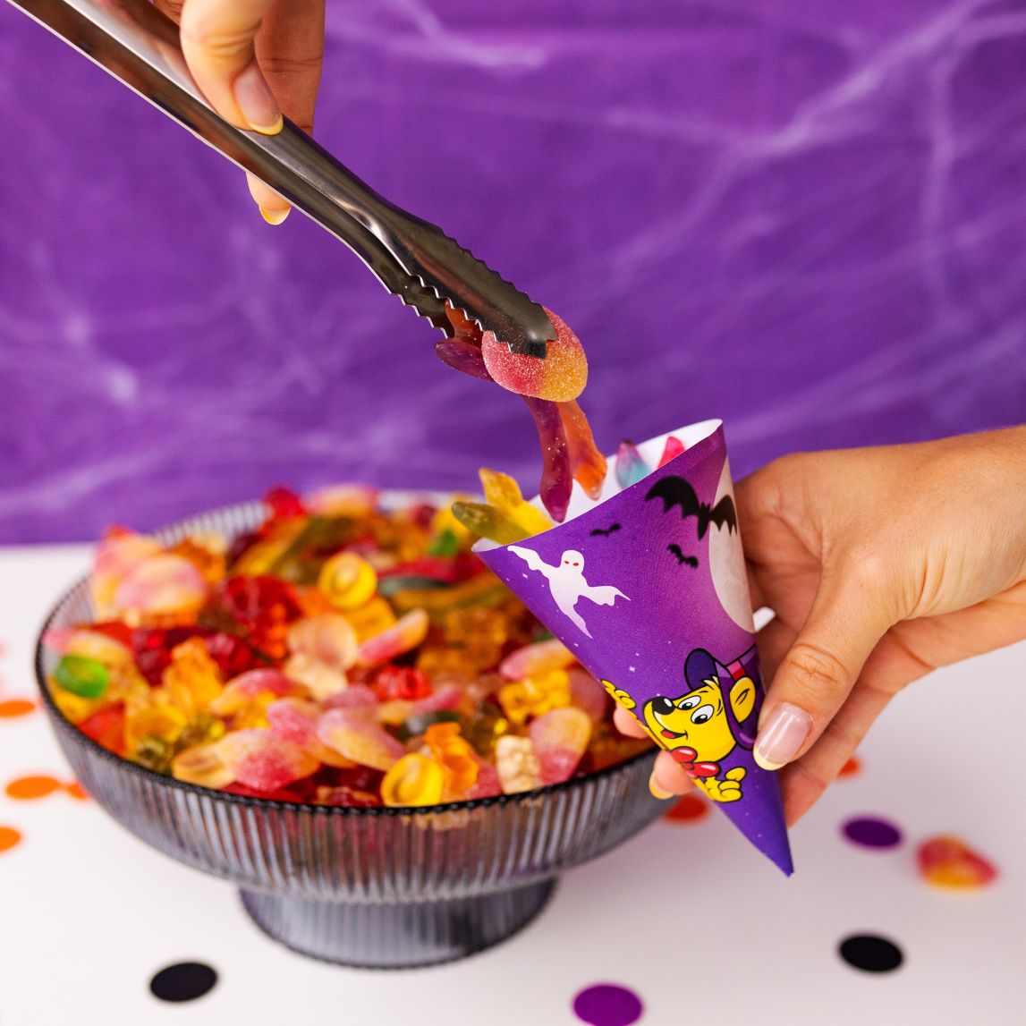 tongs placing product pieces into a paper cone bag