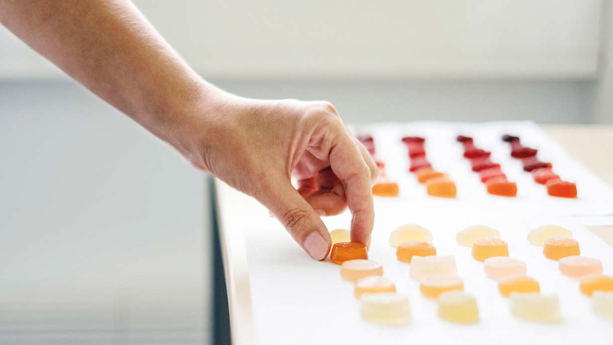 An employee testing the consistency of fruit gummies by hand