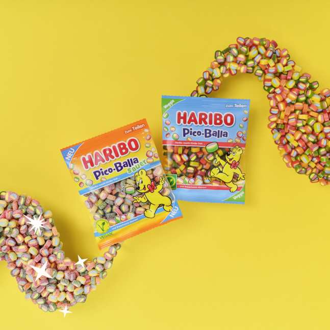 Ein Beutel HARIBO Pico-Balla und ein Beutel HARIBO Pico-Balla Sauer auf gelbem Hintergrund.