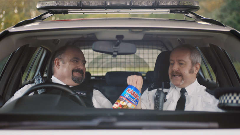 Two police men in their car eating HARIBO starmix