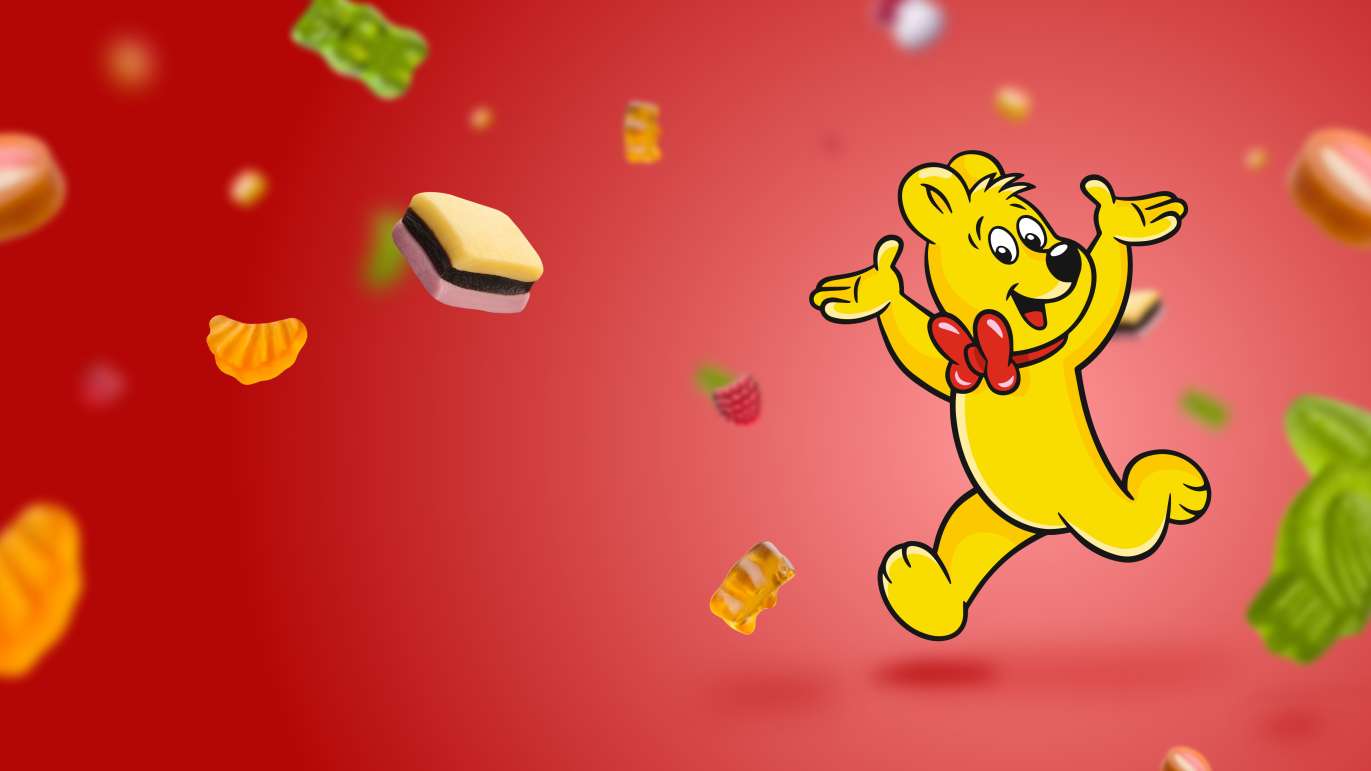 HARIBO Goldbär laufend auf rotem Hintergrund un fliegenden Produktstücken