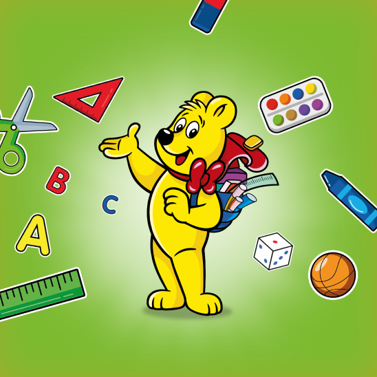 HARIBO maci iskolatáskával a hátán, körülötte iskolás kellékekkel