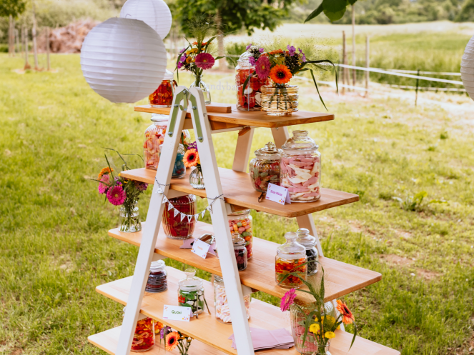 Candy Bar selber basteln: Retro-Glasbehälter, gefüllt mit HARIBO Goldbären. Im Hintergrund sind Blumen und weitere Glasbehälter mit weiteren Süßigkeiten von HARIBO zu sehen.
