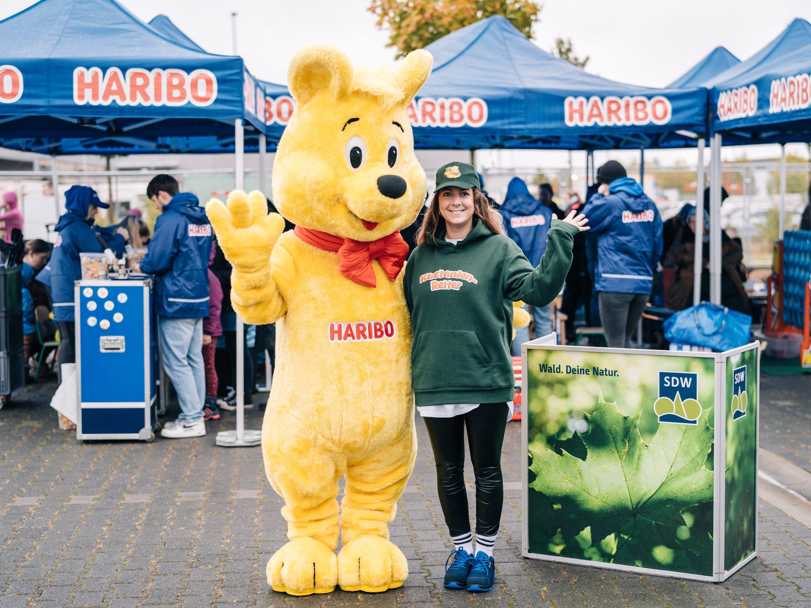 Eine HARIBO-Mitarbeiterin und der Goldbären Walking-Act informieren über die Kastanienrettung.