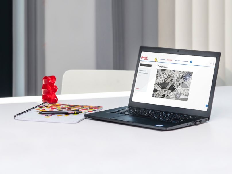 Laptop stands on a table with a large red Goldbear in an office