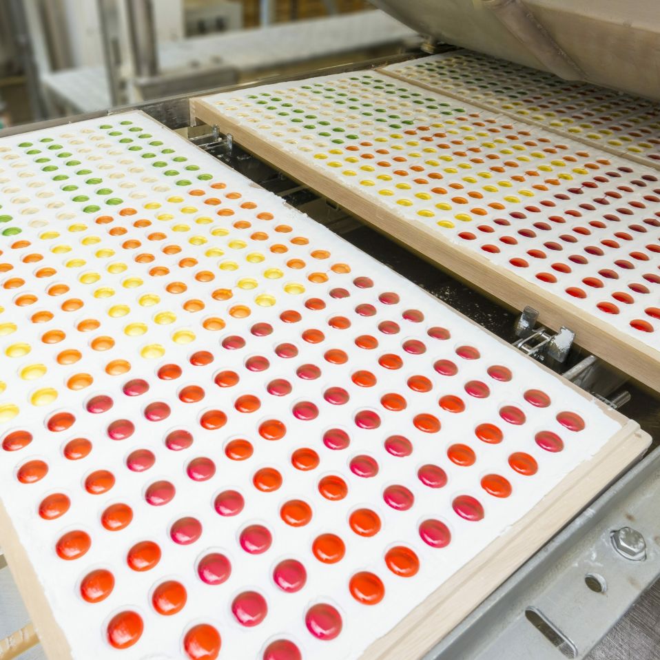 An employee checking the fruit gummy production by machine