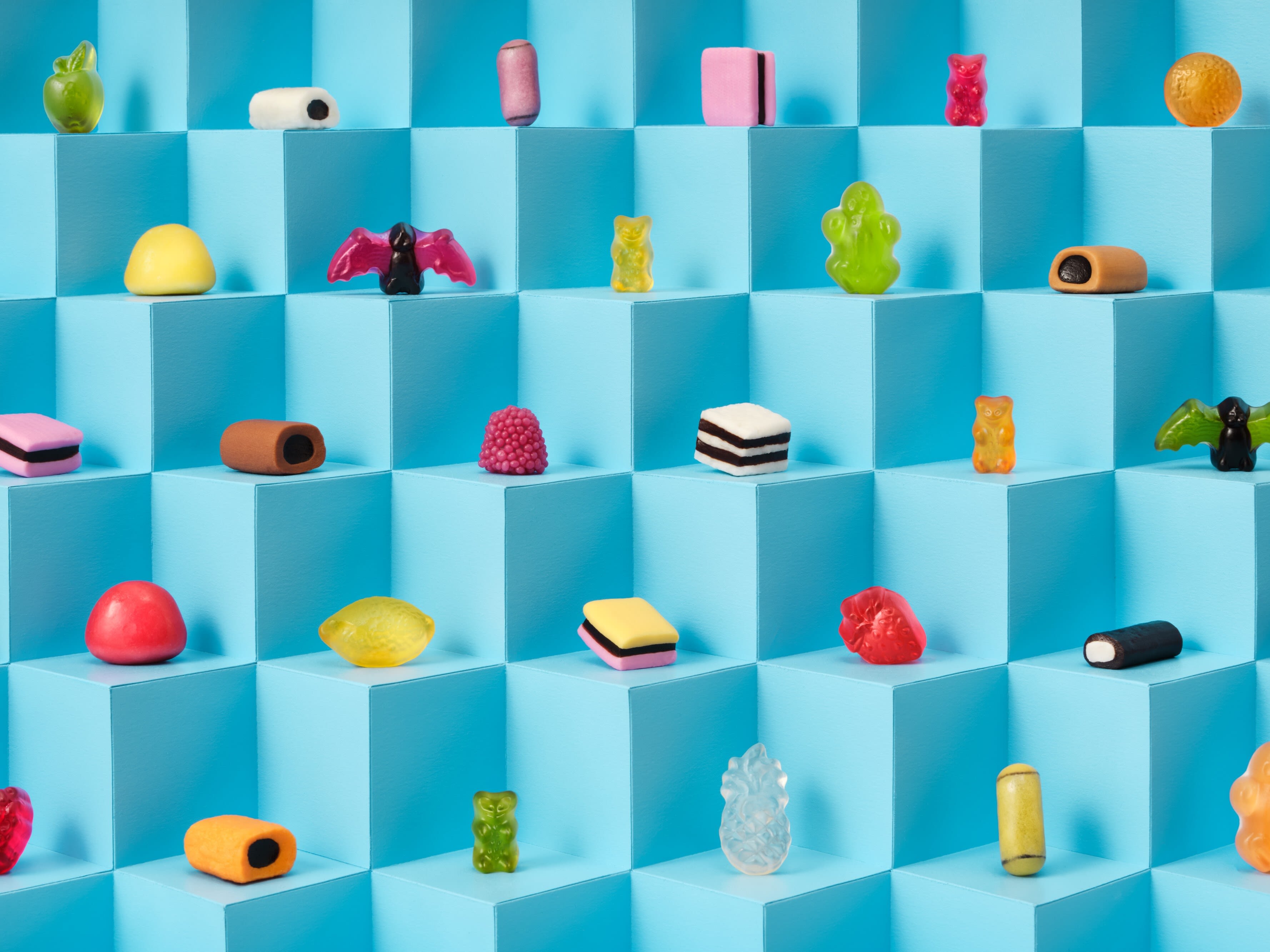 Die bunten Produktstücke aus HARIBO Color-Rado einzeln vor einer blauen Würfelwand.
