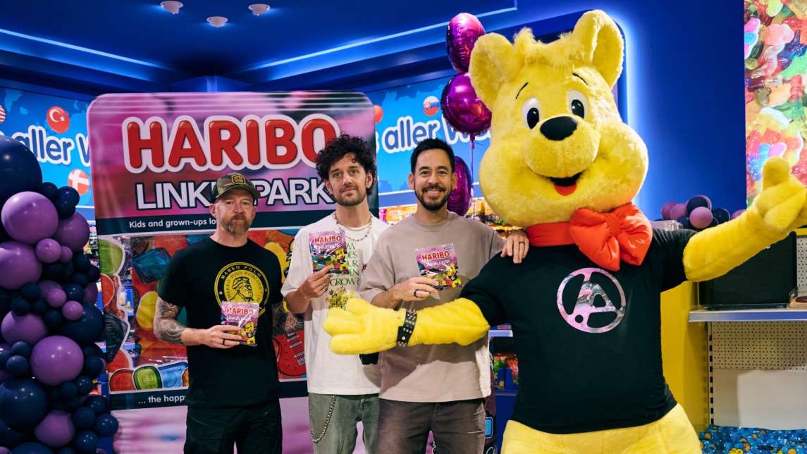 Drei Mitglieder der Band Linkin Park zusammen mit dem gelben HARIBO-Goldbären und ihrer Fruchtgummi-Sonderedition im HARIBO Shop Berlin.
