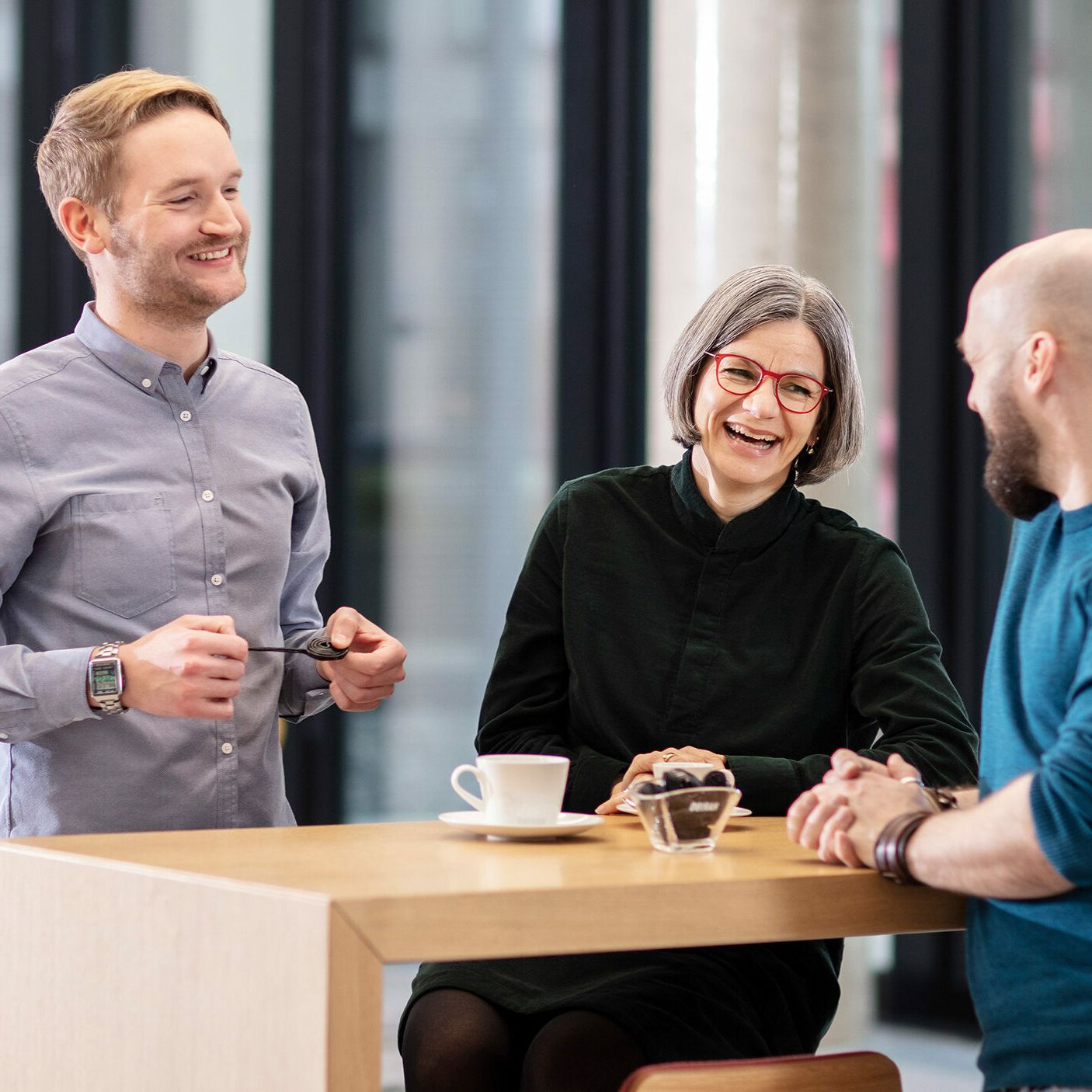 Drei Mitarbeiter unterhalten sich in der Cafeteria
