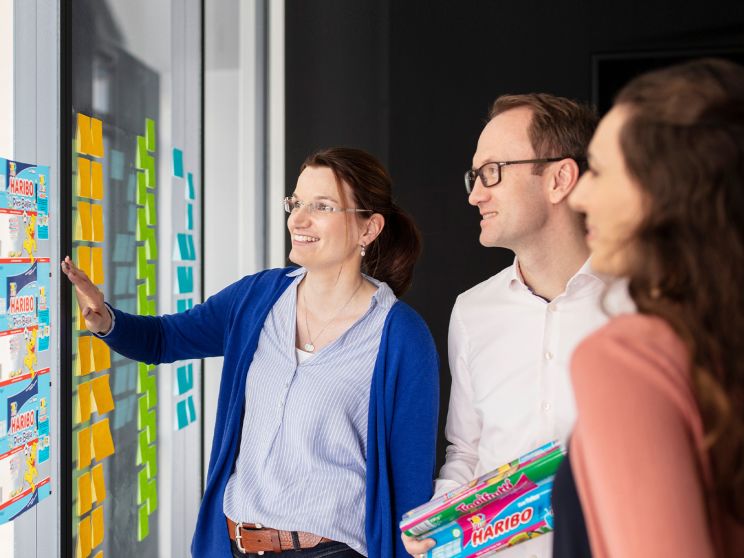 3 Haribo employees in a meeting in front of a wall with post-its