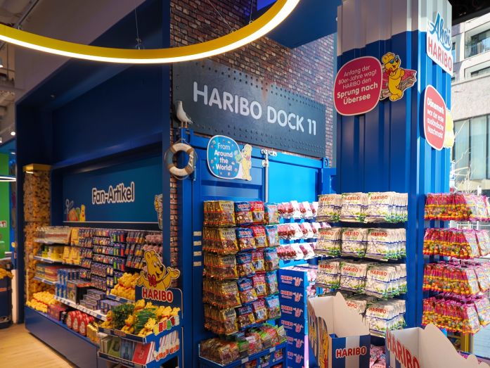 Die HARIBO-Dock-11-Ecke im HARIBO Shop Hamburg mit Regalen voller Fruchtgummi und Fanartikel.