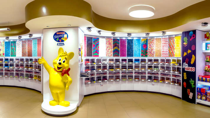 Candy-Bar im HARIBO Shop in Bonn mit großer Auswahl an Produkten und Goldbär im Vordergrund