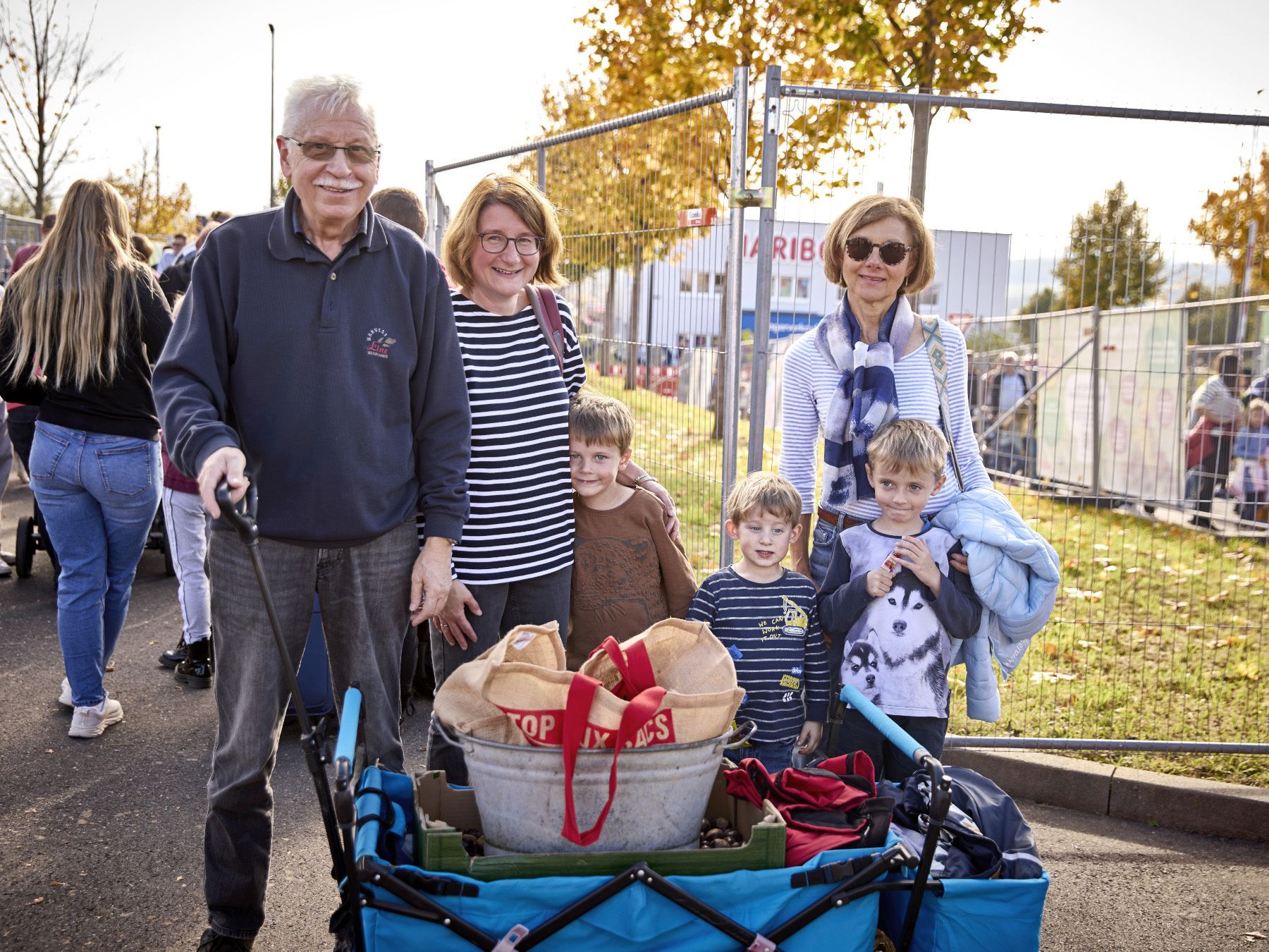 Eine Familie mit Großeltern, Eltern und drei Kindern mit einem Bollerwagen voller Kastanien.