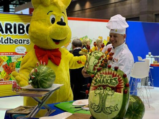 Goldbear and chef with watermelon sculptures at Sweets and Snacks Expo
