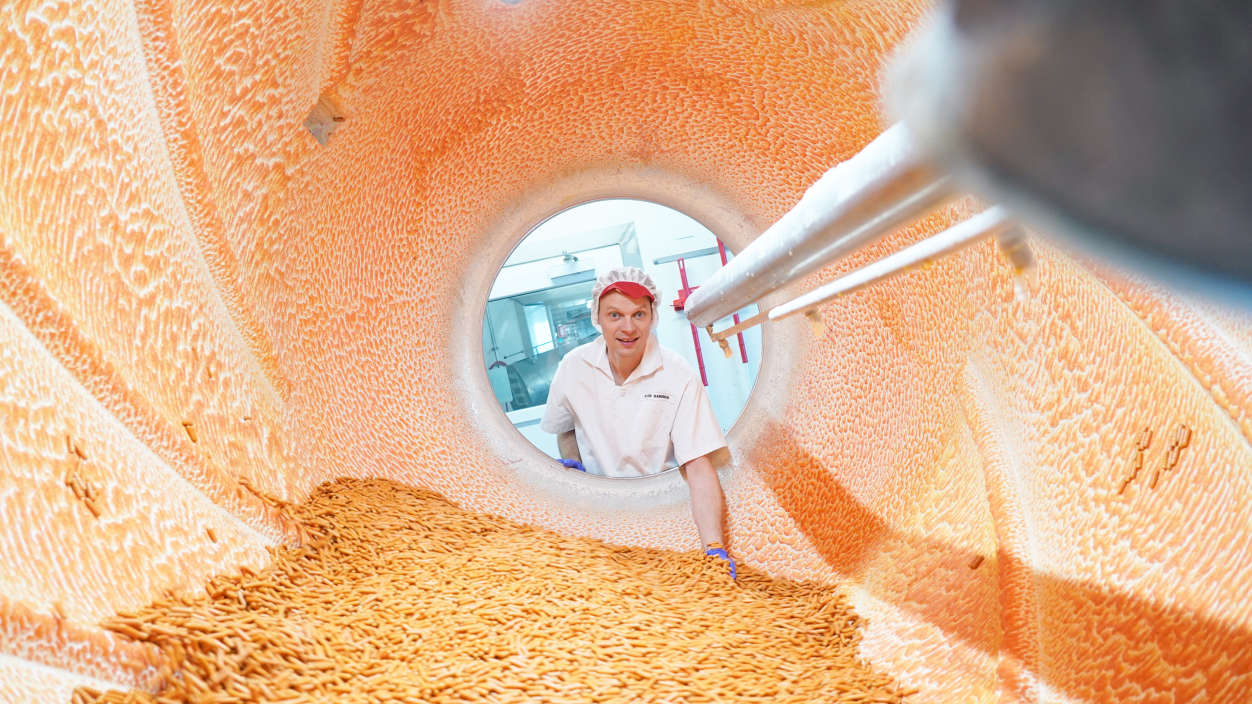 Pohľad dovnútra do výrobného kotla, pracovník sa pozerá cez otvor