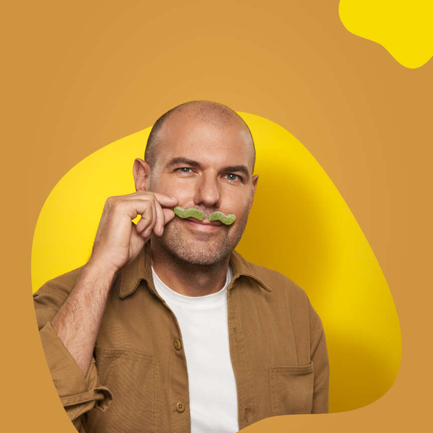 Mitarbeiter trägt einen Schnurrbart aus Fruchtgummi.