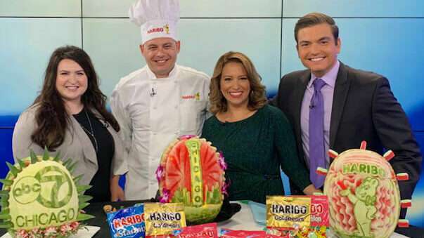 Head of Corporate Communications, Lauren Triffler, Chef and newscasters pose with watermelon sculptures in ABC7 Chicago Studio